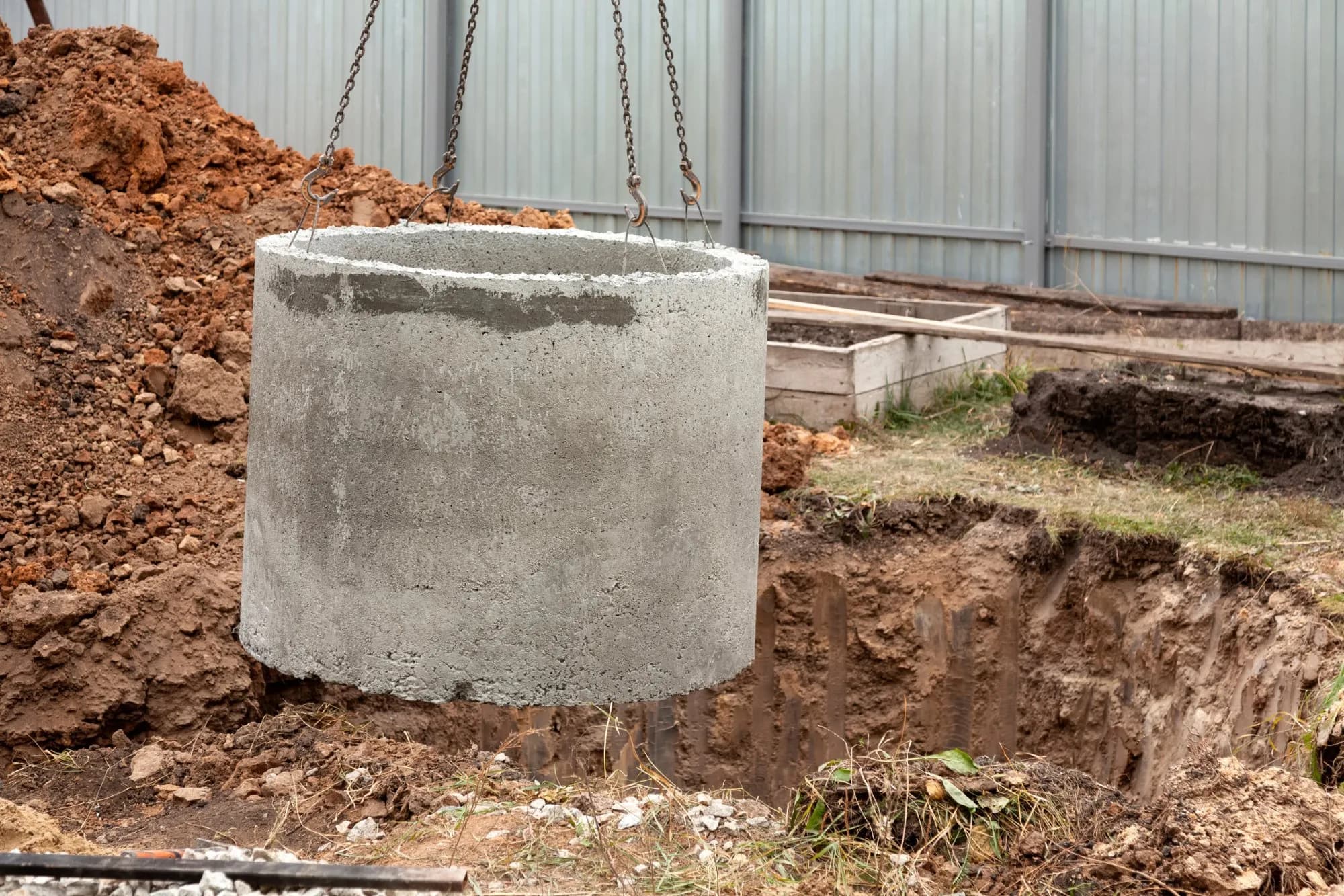 Excavator lifting a concrete ring into an excavation — an everyday operation that still requires a LOLER lift plan