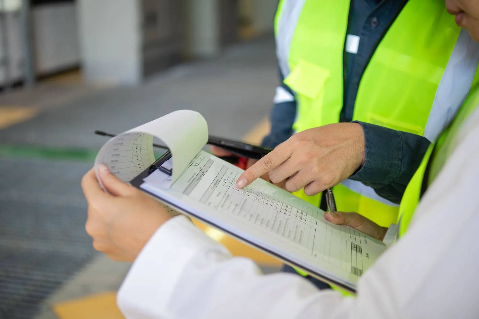 Inspector reviewing lifting documentation on a clipboard at a UK construction site — the scrutiny a lifting plan must stand up to