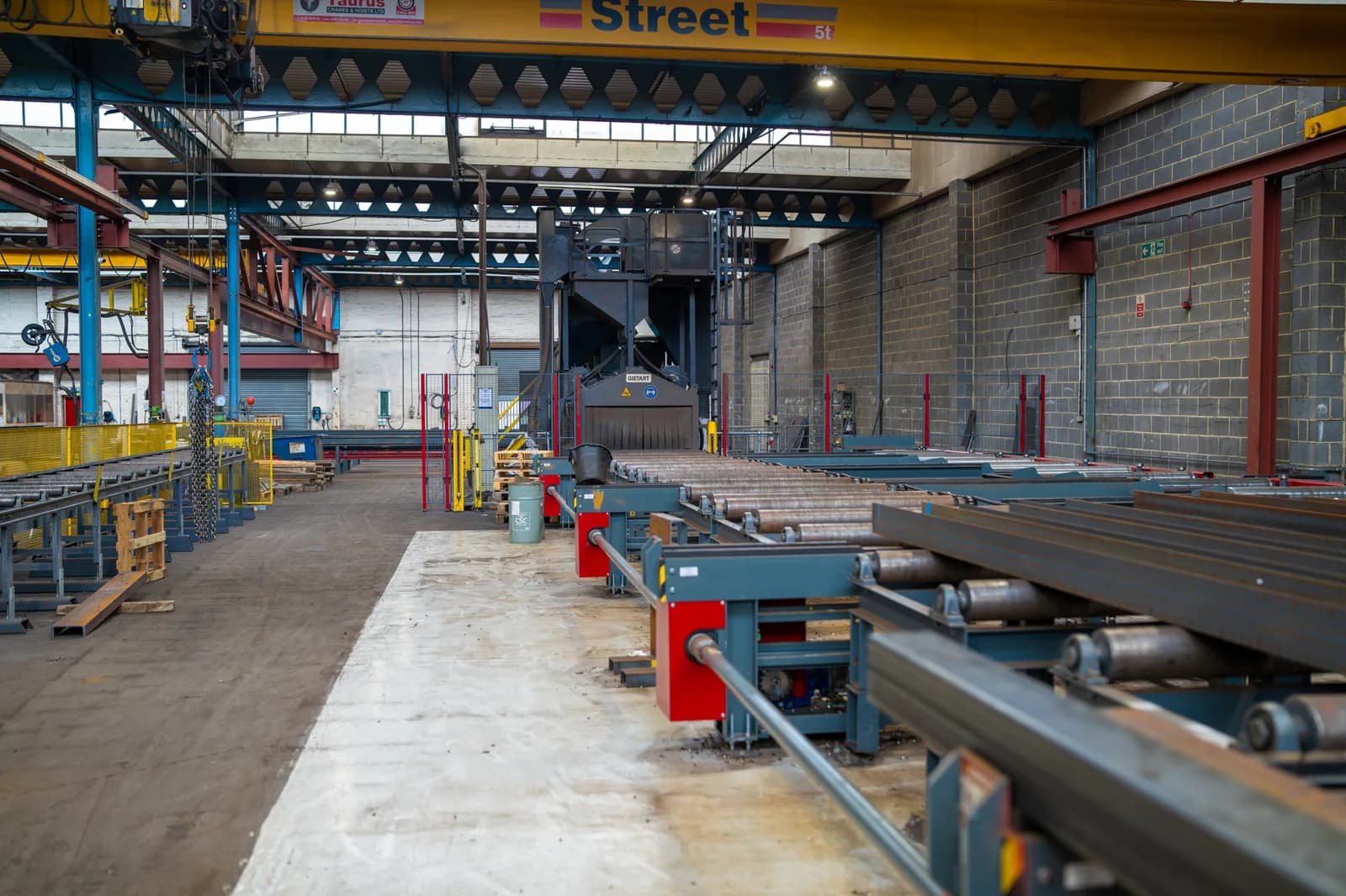 Overhead travelling bridge crane lifting a steel load inside a UK factory — overhead crane lifting operation under LOLER and BS 7121-7
